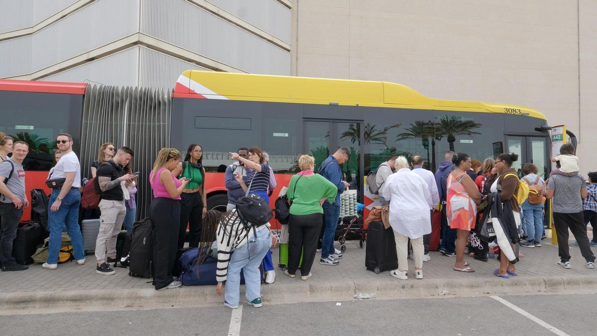 Turistas haciendo cola en el aeropuerto para subir a un autobús interurbano