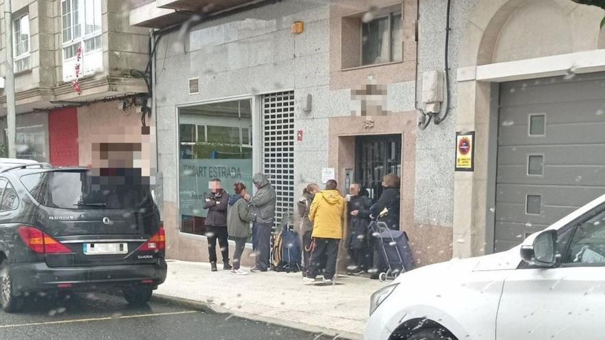 Imagen de las colas en el portal del edificio en el que se presta el servicio y cartel en su interior.