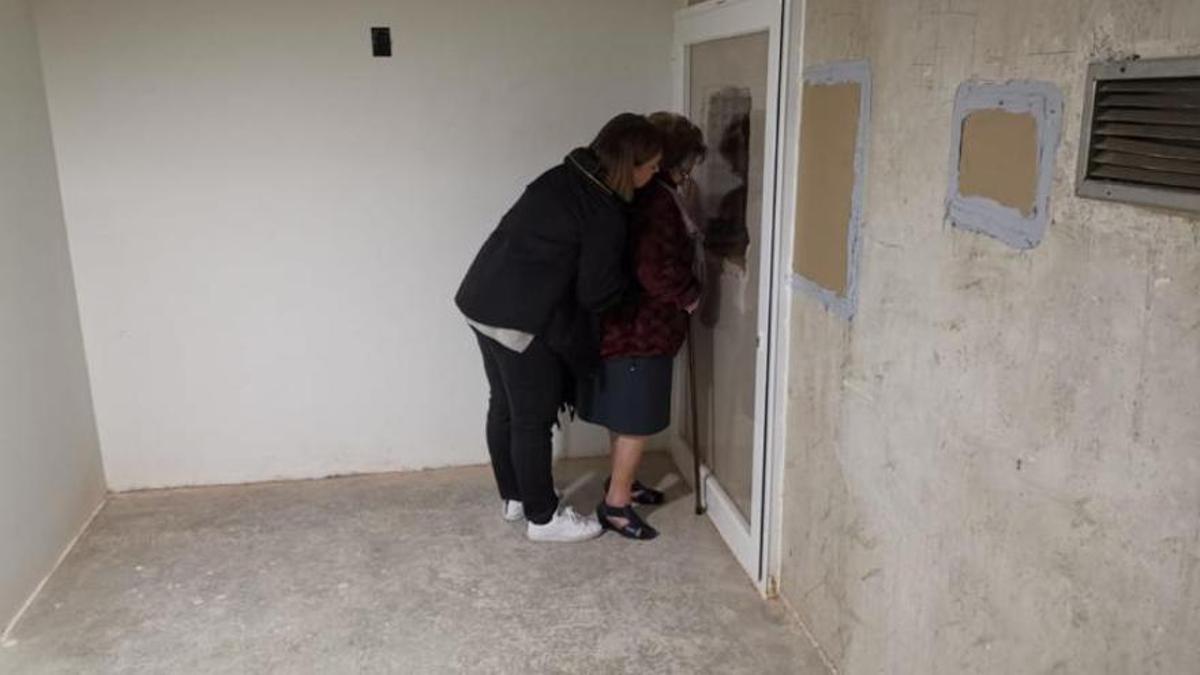 Familiares de enterrados en el Valle de los Caídos se asoman a un agujero en la pared de una cripta intentando ver las cajas de sus parientes en marzo de 2018.