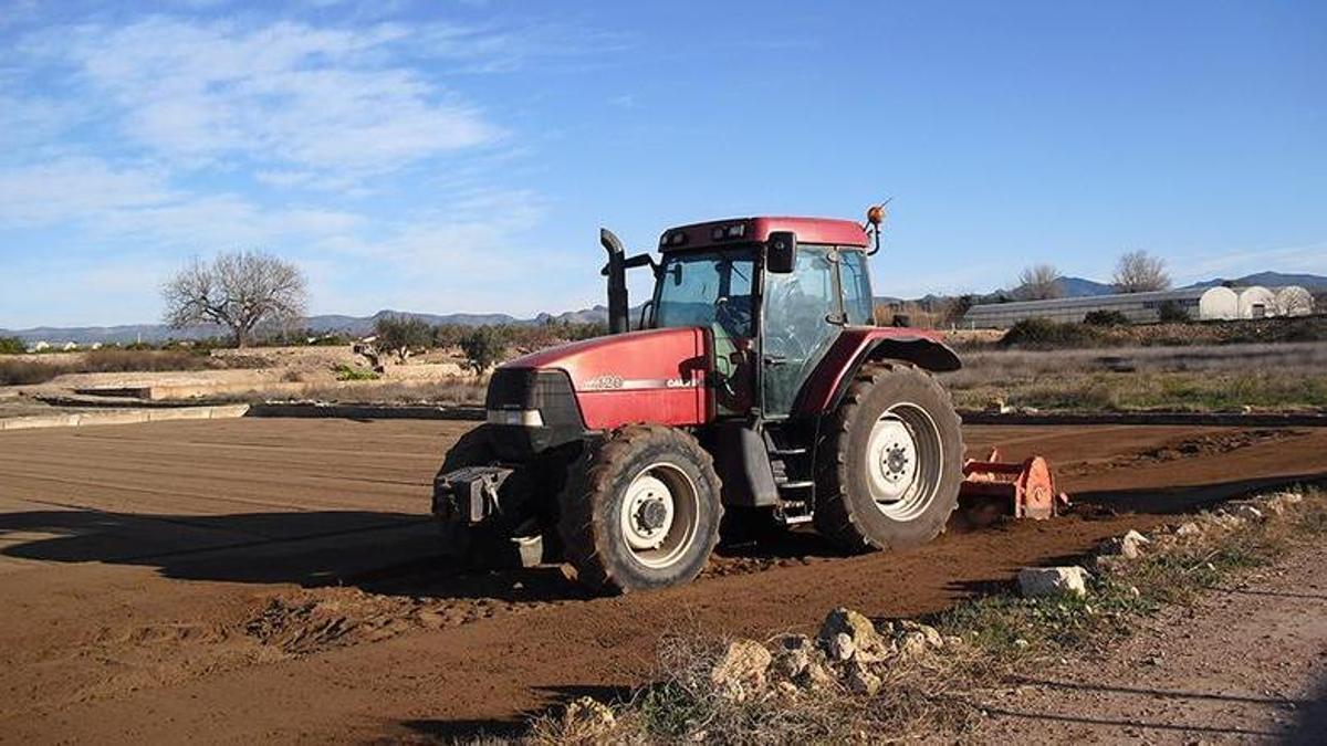 Un agricultor con su tractor en una finca.