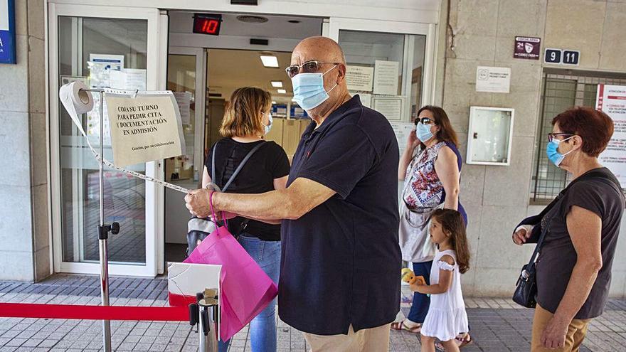 Usuarios cogen número de un gotero para pedir cita en el centro de salud de Florida (Alicante) sin tener que hacer cola en la calle.