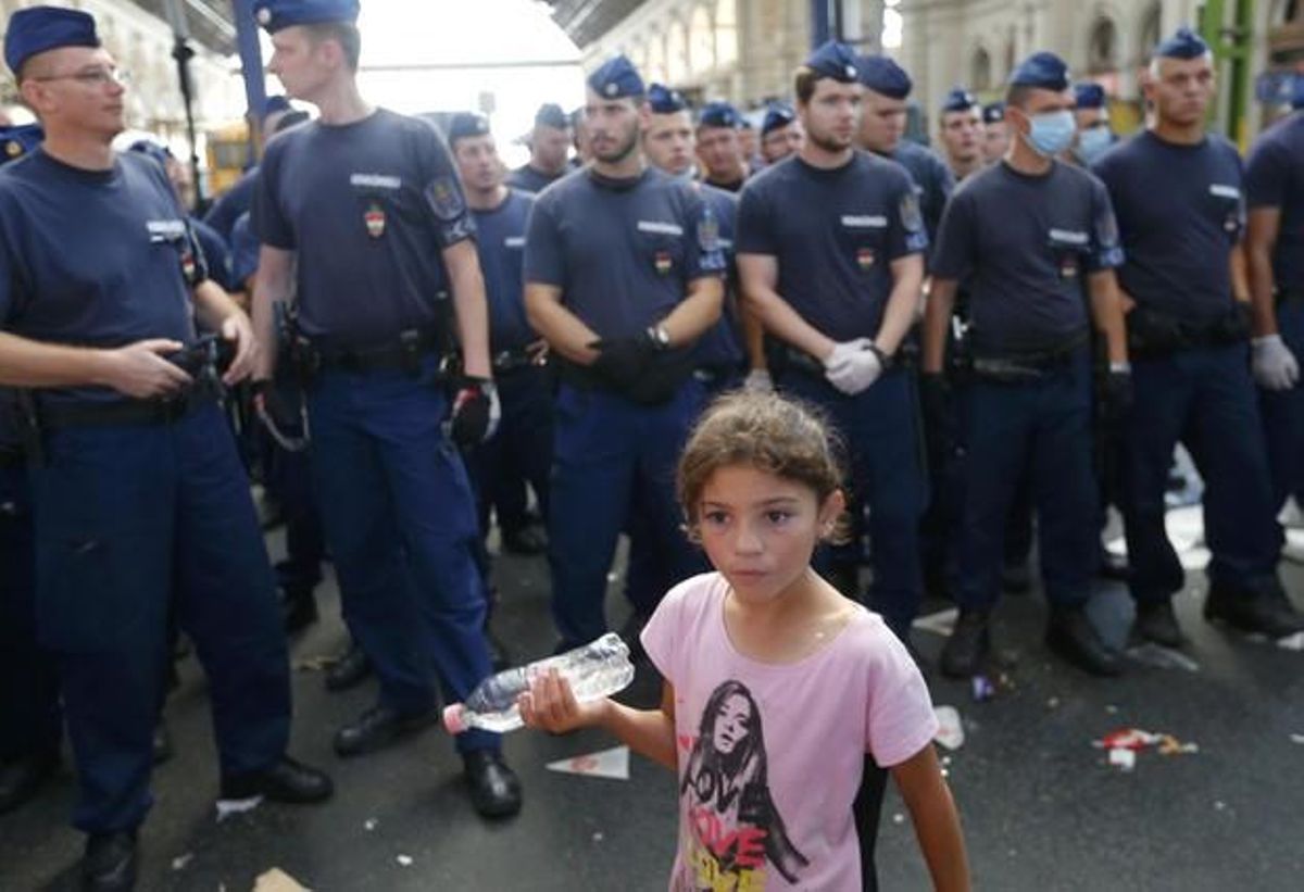 Una nena fotografiada davant dels policies que impedeixen l’entrada d’immigrants a l’estació de trens de Keleti, a Budapest, aquest dimarts.
