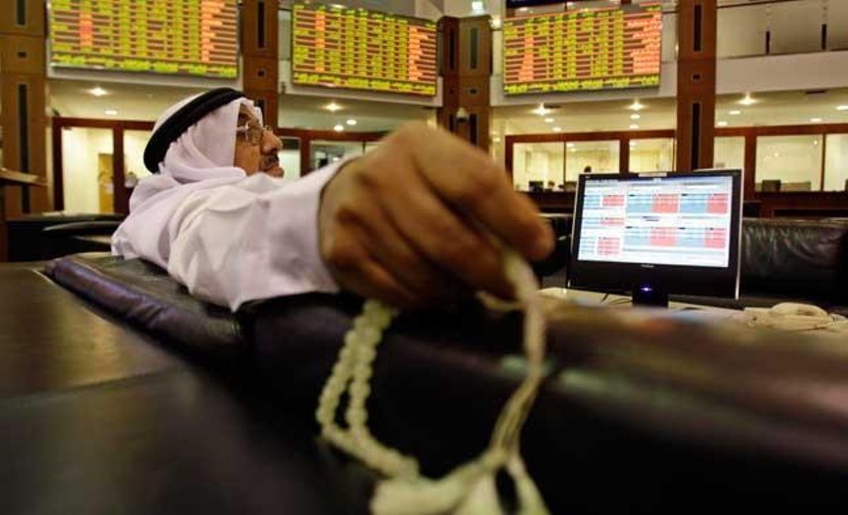 Un comerciant sosté una corda de pregàries mentre controla els últims resultats del mercat financer de Dubai, als Emirats Àrabs Units.