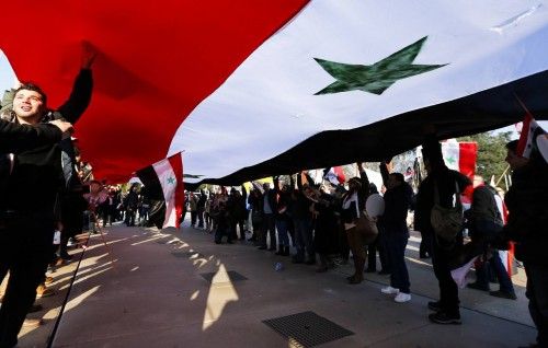 Supporters of Syrian President al-Assad carry a Syrian flag in front the United Nations European headquarters in Geneva