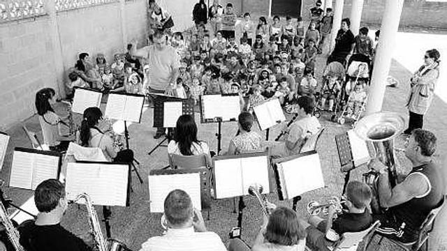Miembros de la Banda y la Joven Banda de Laviana tocan una pieza ante los alumnos del taller.