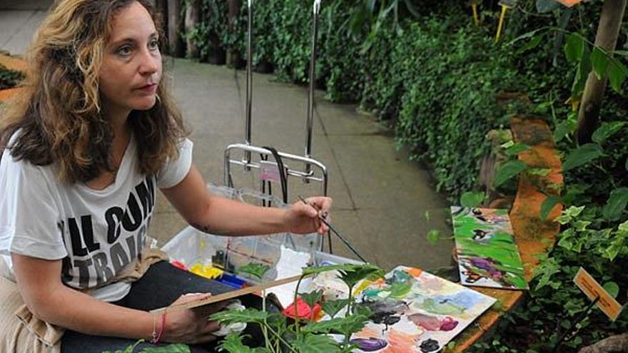 La pintora mira para una mariposa junto con unos visitantes.