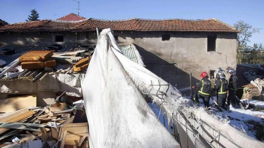 Los bomberos, durante los trabajos de extinción del incendio en la vivienda.