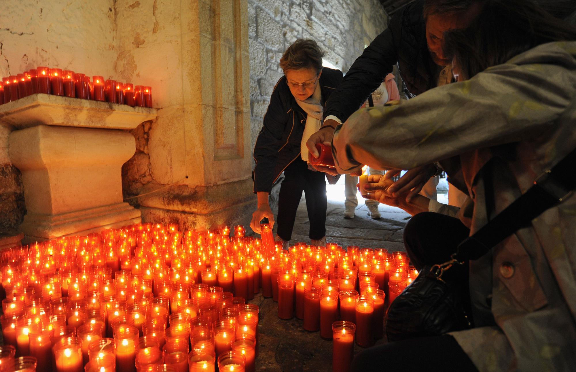 Un grupo de fieles enciende cirios, en el interior de la capilla.