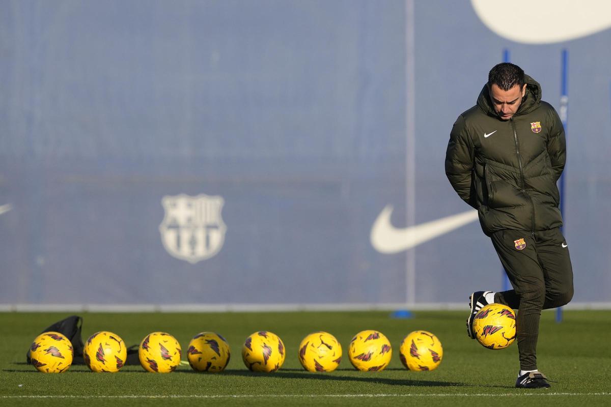 Xavi juguetea con un balón mientras espera la llegada de los futbolistas al entrenamiento.
