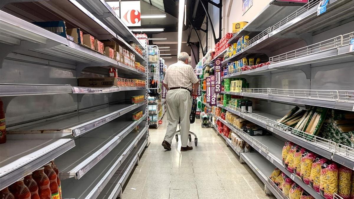 Un hombre camina entre estantes vacíos en un supermercado de Buenos Aires, este domingo.