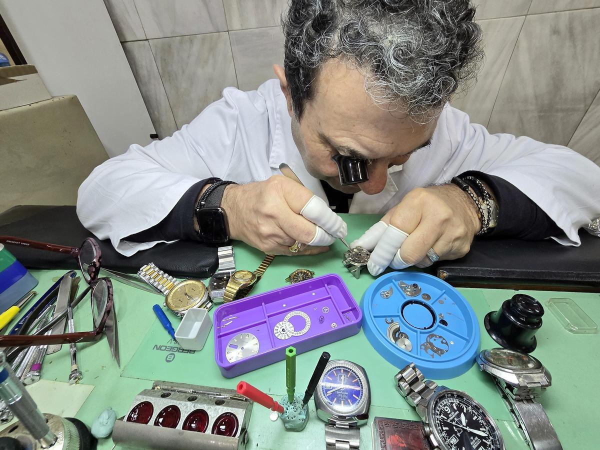 Manolo Olegario reparando un reloj antiguo en su taller de la calle Pizarro