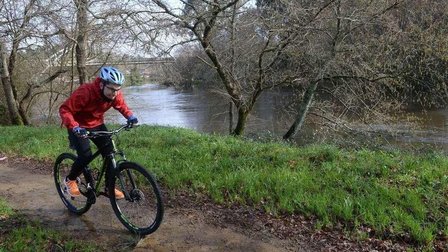 Un ciclista pasa por la senda del Umia cuando este tuvo su mayor caudal, en el temporal de febrero. // NP