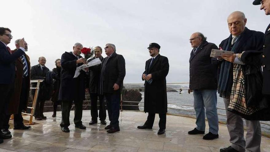 Los asistentes al acto en el Museo de Anclas se disponen a lanzar flores al mar en La Peñona.