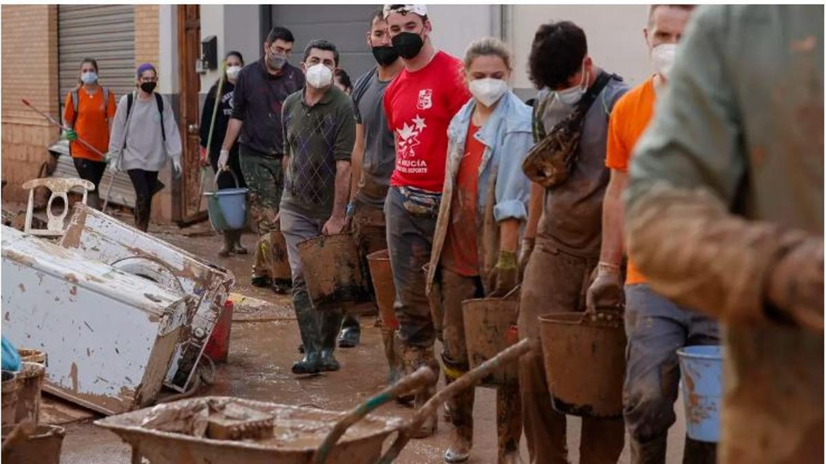 Cadena de jóvenes en labores de limpieza tras la dana.