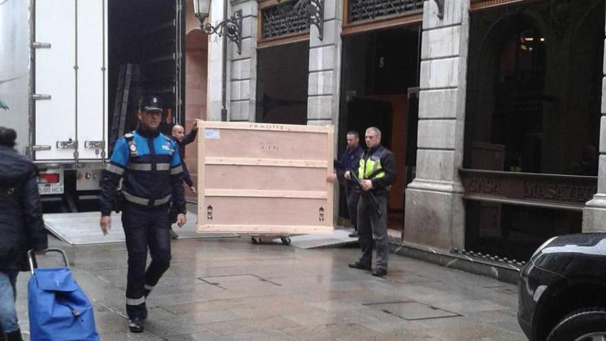 Trabajadores llevando al camión una de las obras para su transporte.