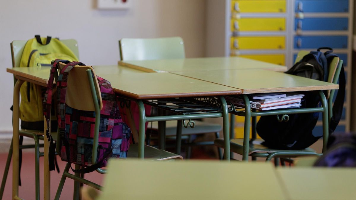 Varios pupitres en un aula vacía.