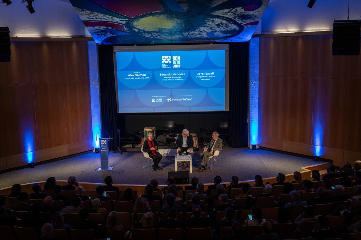 El escritor Eduardo Mendoza conversa con el músico y director de orquesta Jordi Savall en un diálogo moderado por Álex Sàlmon durante el acto celebrado en Barcelona, a 16 de junio de 2026.