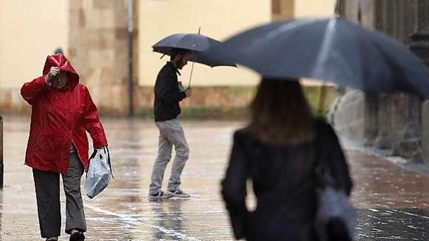 Los viandantes se protegen de la lluvia, ayer, en Oviedo.