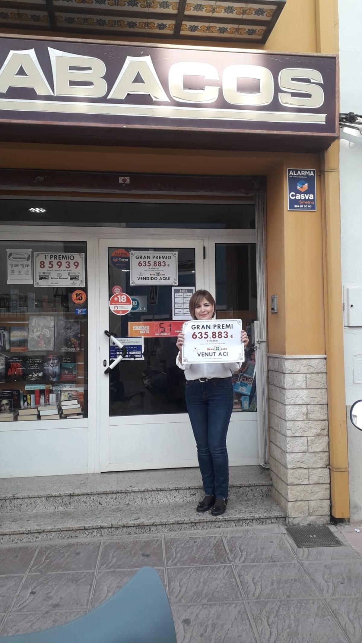 Emilia Tomás posa con el cartel delante de la puerta del estanco.