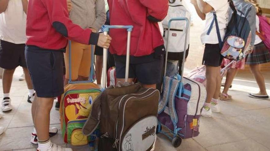 Niños con sus mochilas a las puertas de un colegio.