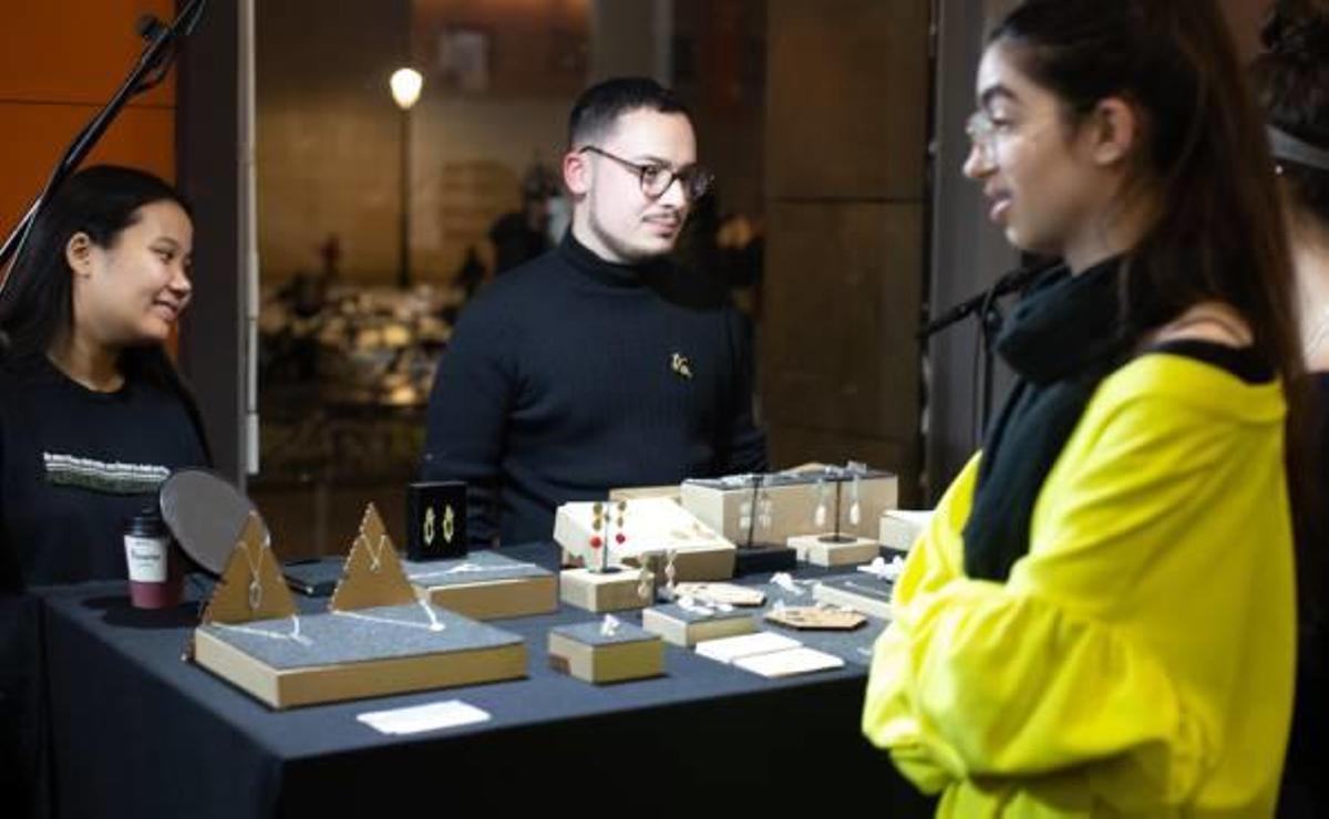 Joves dissenyadors en la paradeta en la qual mostren les joies que han creat.