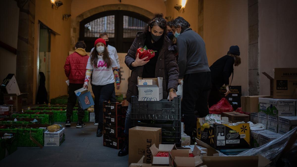 Varios voluntarios de la asociacion Actua Ayuda Alimenta (AAA) preparan cestas de alimentos para trabajadores del sector cultural en Barcelona.