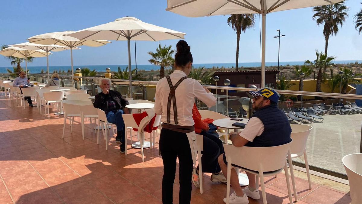 Varios turistas toman un tentempié y disfrutan del buen tiempo junto al mar en la terraza del Gran Hotel Peñíscola. Son muchas las plantillas que se empiezan a reforzar de cara a Semana Santa.