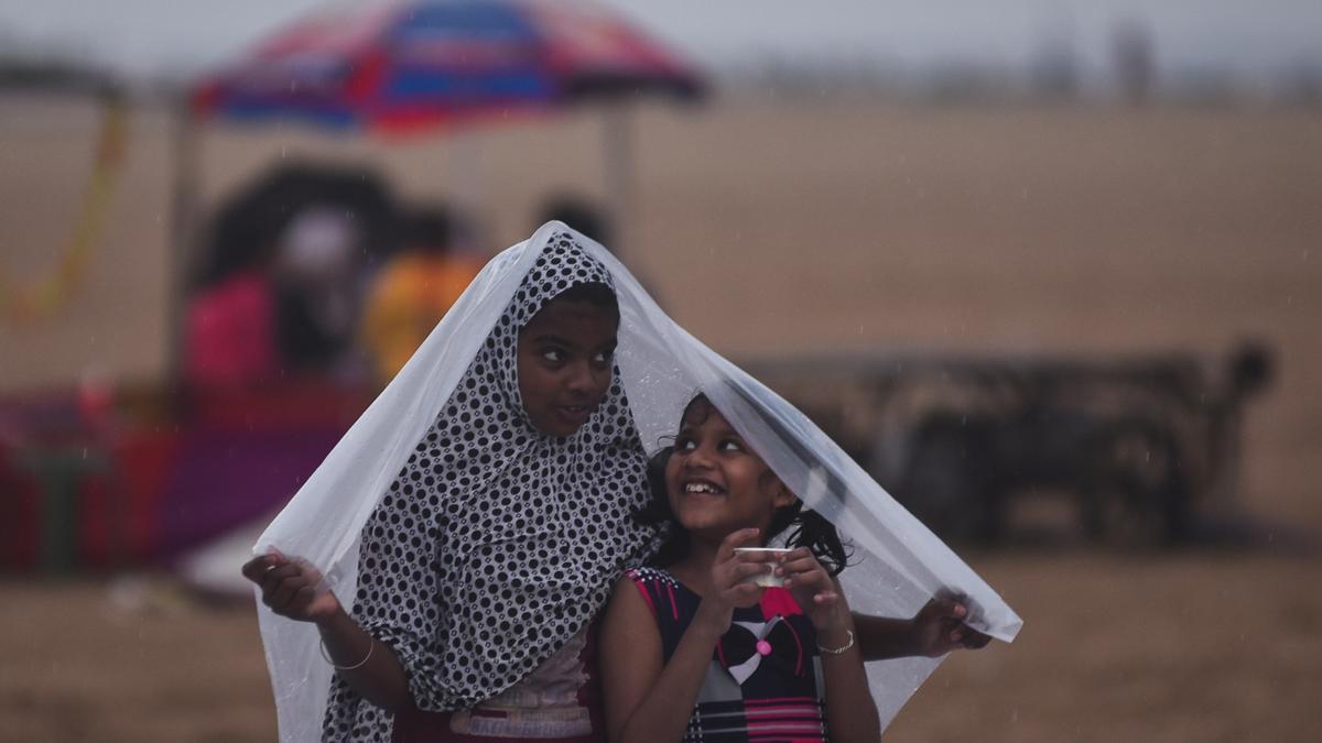 Unas niñas se cubren de las lluvias en la India.