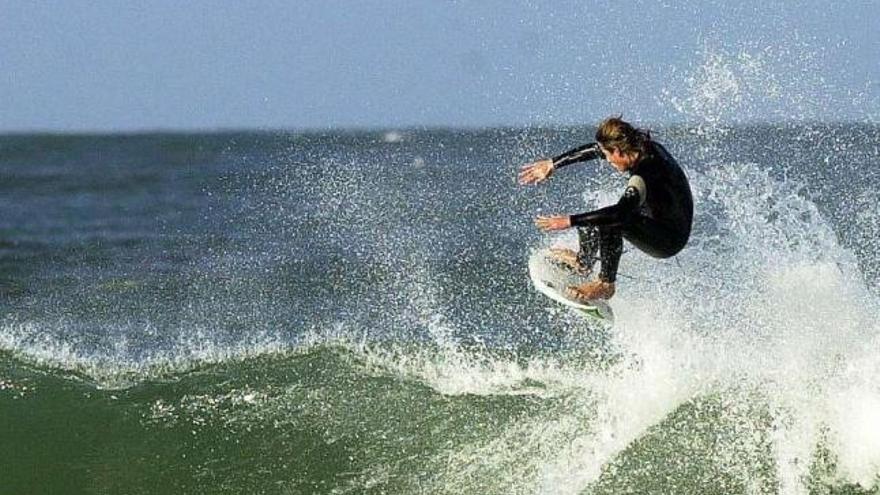 Joven practicnado surf en la playa de Patos, en Nigrán.  // FDV