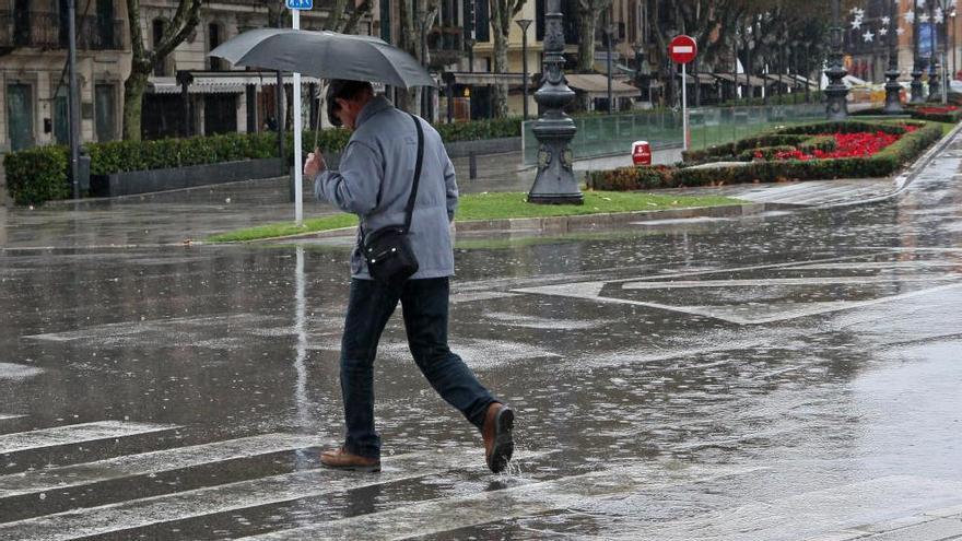 Un ciudadano se protege de la lluvia en el Passeig Sagrera de Palma