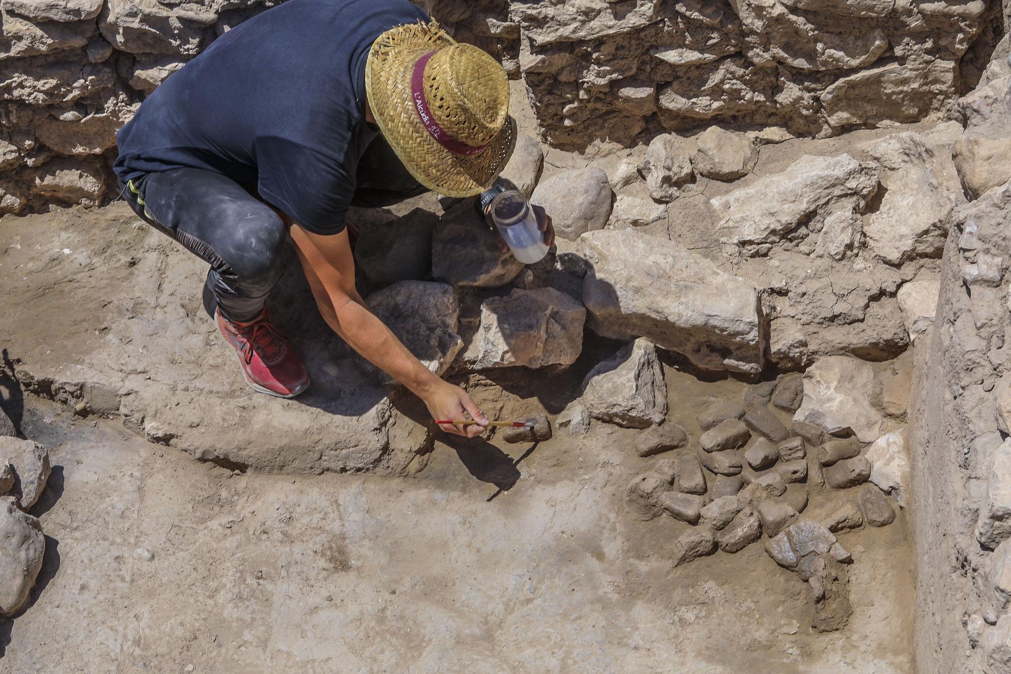Uno de los arqueólogos de la UA pone un líquido a las pesas de telar íberas para evitar su deterioro.