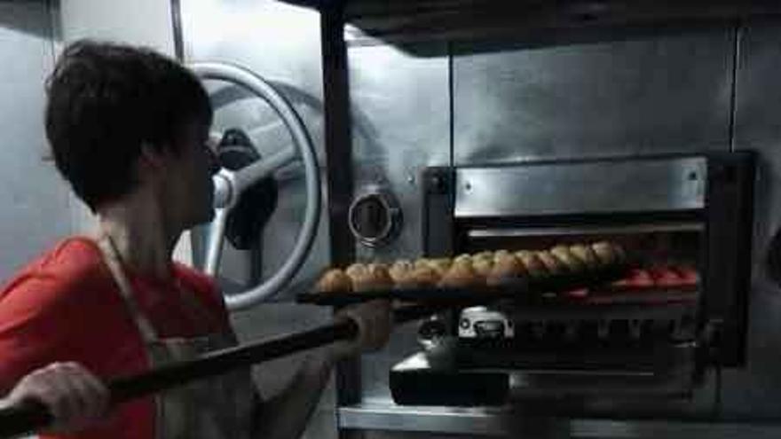 La panadera de Corrales mete las magdalenas en el horno.