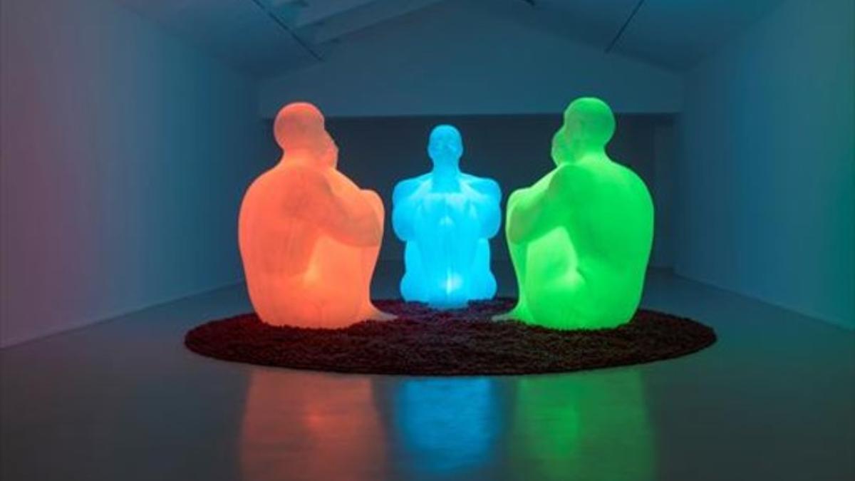 Tres figuras de resina iluminadas de diferentes colores forman 'Air, Water, Void'.