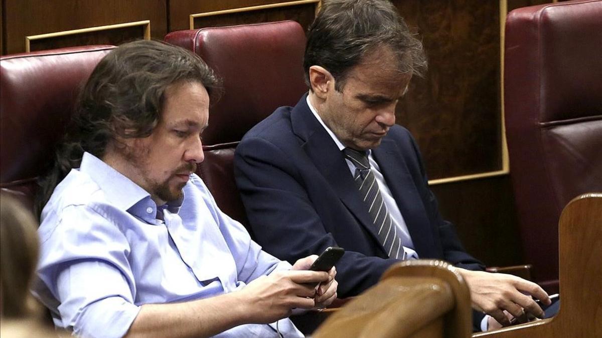 Pablo Iglesias y Jaume Asens consultan sus móviles en el segundo día del debate de investidura de Pedro Sánchez