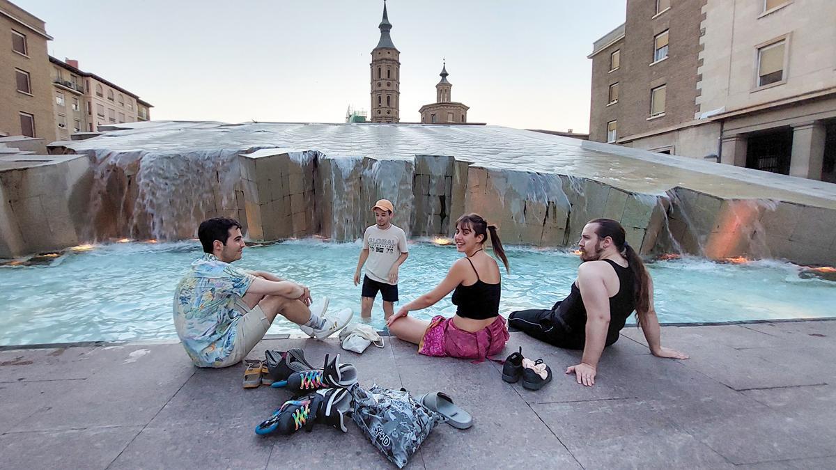 Unos jóvenes se refrescan en una fuente de la plaza del Pilar, en Zaragoza