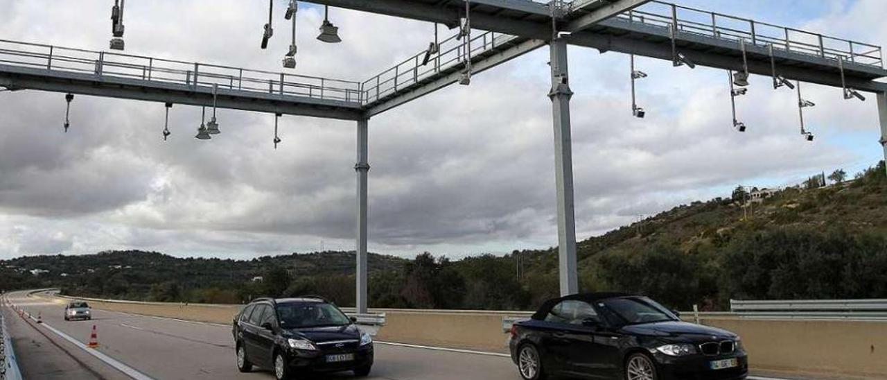 Coches pasan bajo los arcos que identifican las matrículas para el cobro de peajes en una autovía lusa . // FdeV