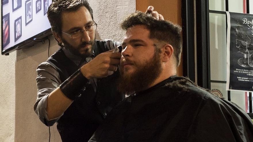 El barbero cordobés Juan Aguilar con un cliente.