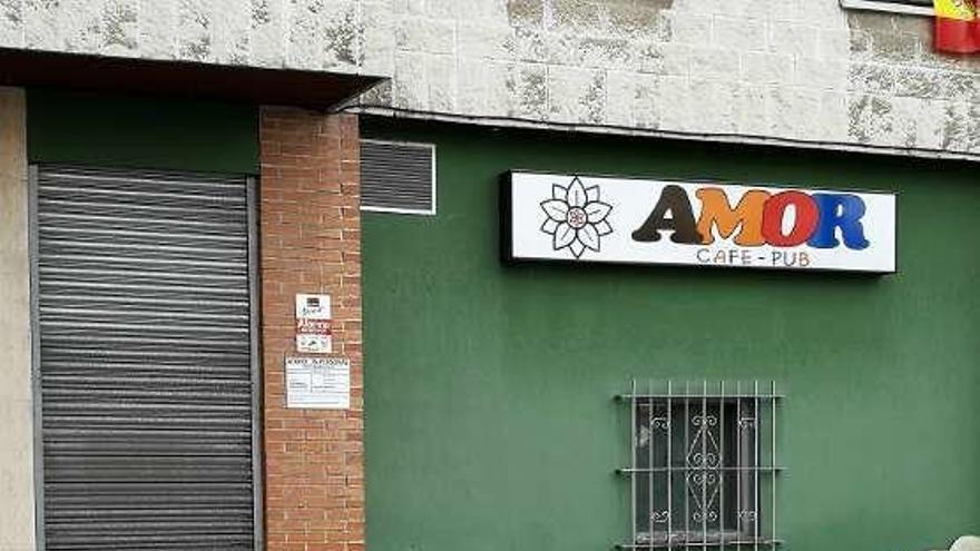 Un policía nacional cierra la verja del local de Lugones donde se produjo el apuñalamiento.