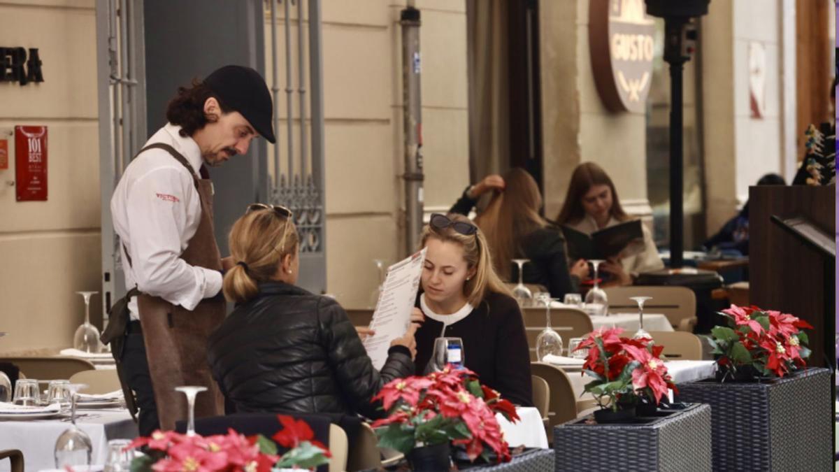 Un camarero atiende a unas clientas en un restaurante de Málaga.