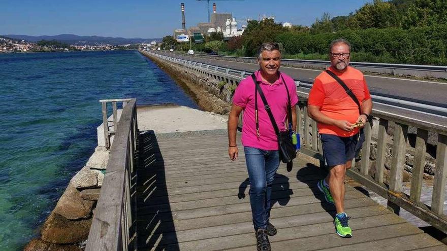 Dos hombres pasean por la &quot;pasarela de mariscadoras&quot; de Placeres, con la que se enlazará el nuevo paseo, por un margen de la PO-11. // S.A.