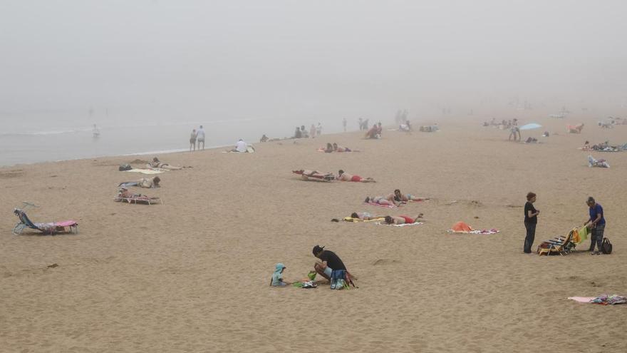 Bañistas en la playa de San Lorenzo (Gijón), con una densa bruma