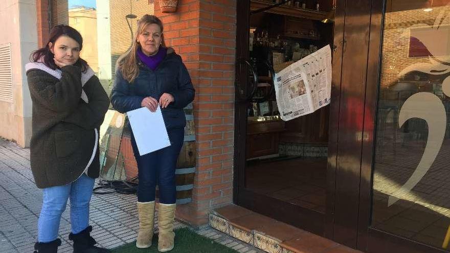 Irene García y María José García, al lado del cristal roto en su negocio de Grado.