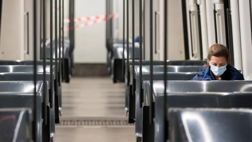 Una dona, sola i amb mascareta en un vagó del metro de Barcelona