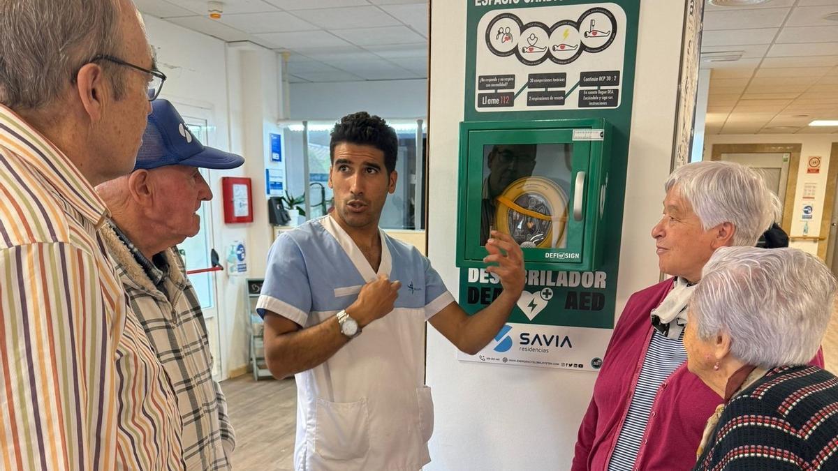 Un trabajador de una de las residencias Savia explica a los usuarios cómo funciona el dispositivo.
