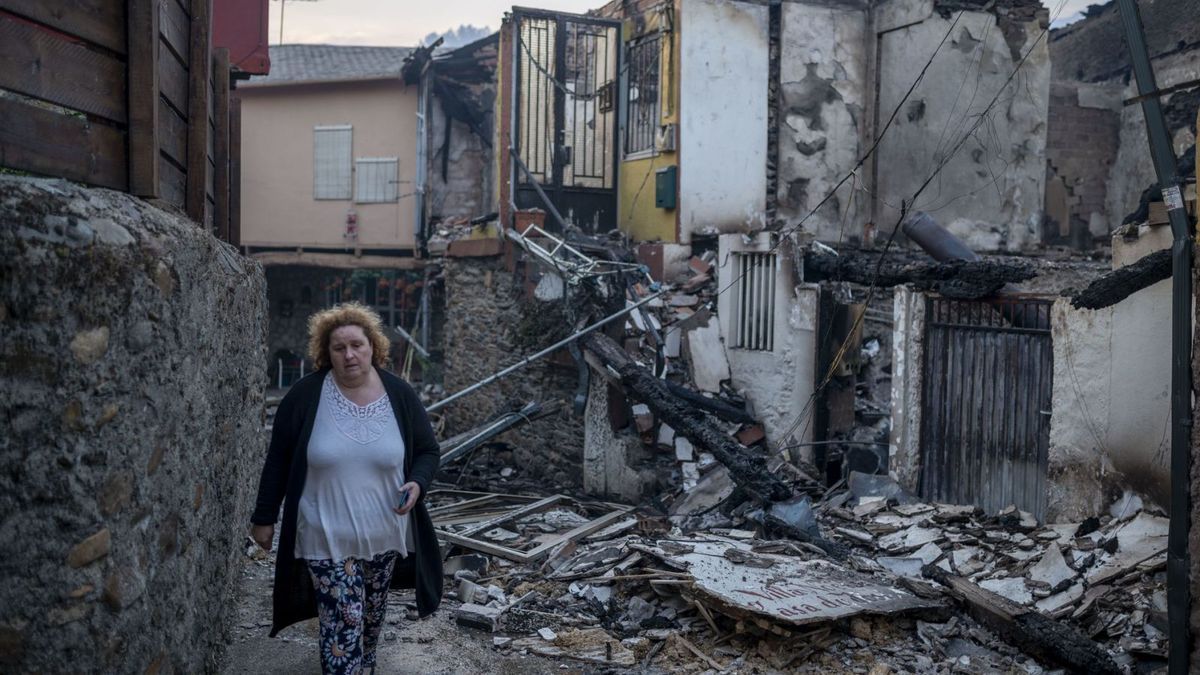 Una vecina de la localidad de A Veiga de Cascallá pasa entre las casas destruidas.