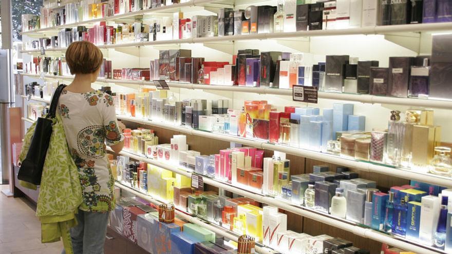 Una mujer delante de un lineal con productos de perfumería.