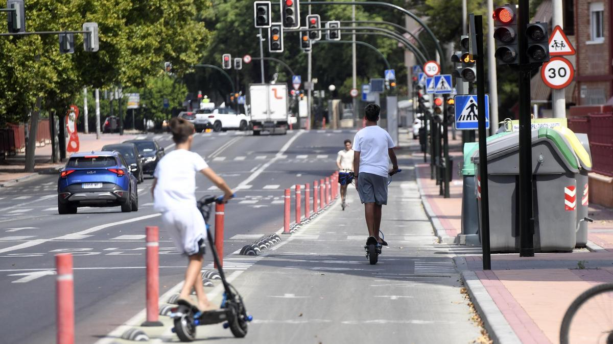 Tres personas circulan en sus patinetes en una calle de Murcia.