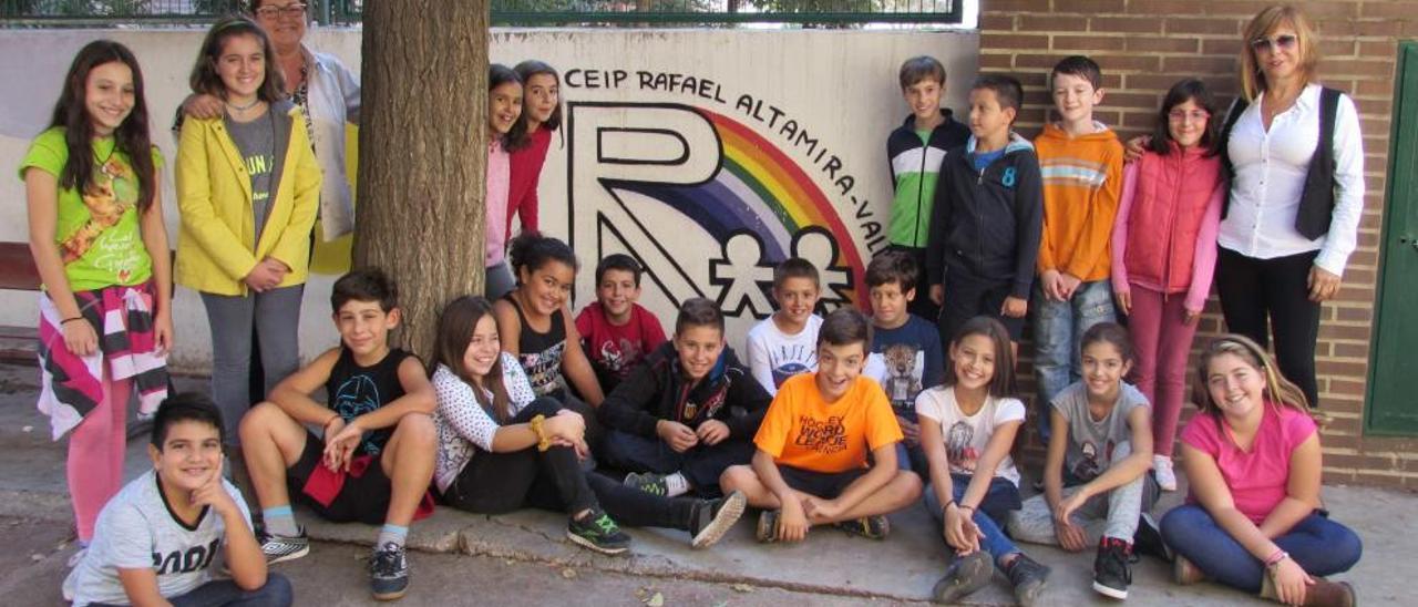 El grupo de 5º de Primaria junto al logo del colegio y sus  maestras Empar Tornero (izq.) y Estrella Piqueras (dcha.).