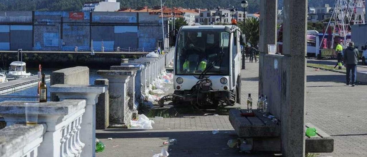 Los trabajadores de la concesionaria, limpiando los restos del botellón de las fiestas de Santa Rita del año pasado. // Iñaki Abella