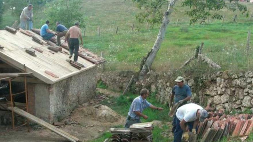 Los vecinos de  San Román, en Piloña, reparan  su lavadero en  una sextaferia